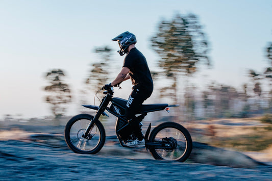 A rider with a helmet on his riding times ride going through an off road hilly trail.