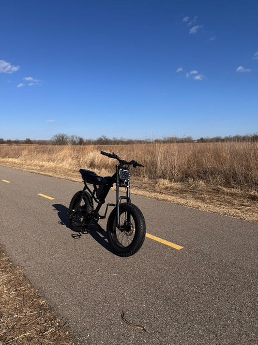 Electric off-road eBike on paved trail with dry grass and clear blue sky