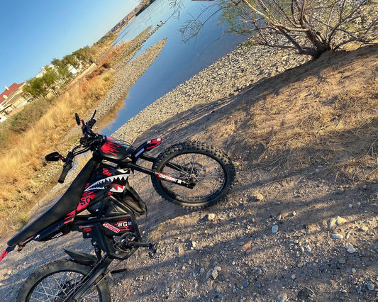GT73 electric dirt bike with custom vinyl wraps and off-road tires near riverbank trail