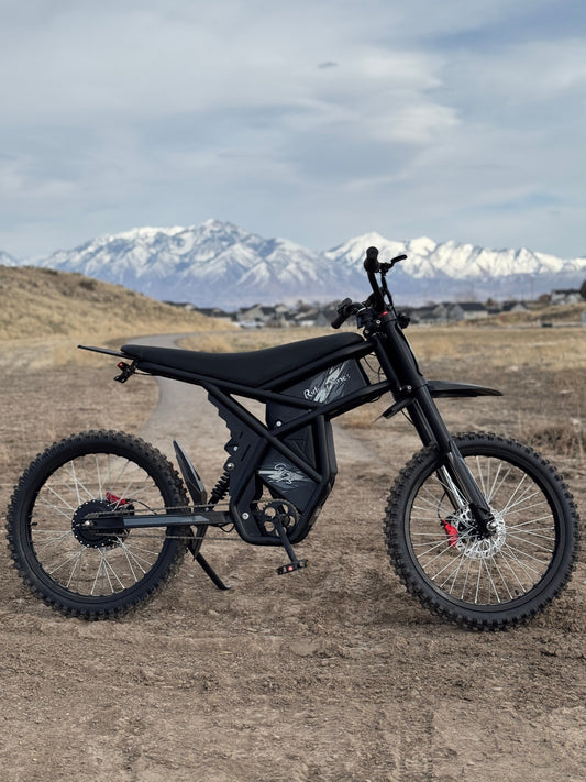 Black electric dirt bike on rough terrain with mountains in the background, illustrating eBike vs. Traditional Bike comparison