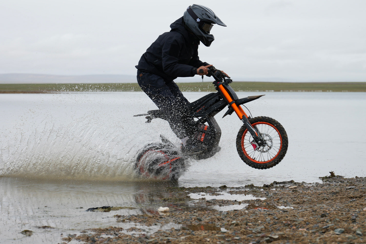 GT54 electric mini motorbike for kids and adults riding through water and splashing on rocky terrain