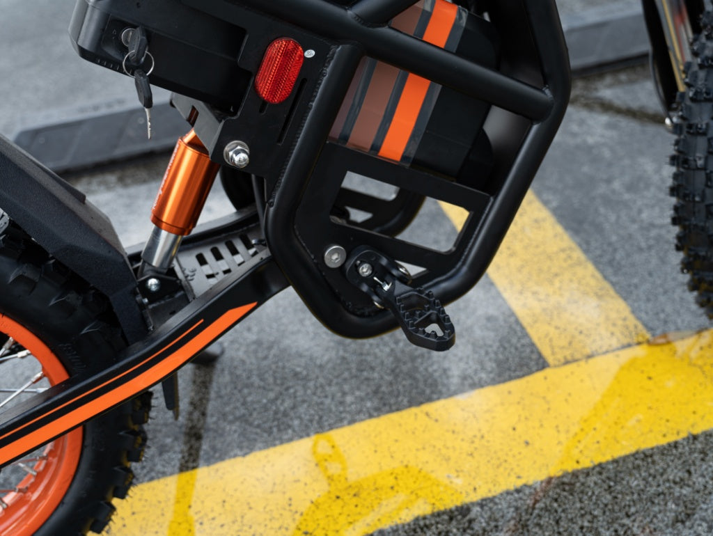 Close-up of GT54 electric mini motorbike pedal and motor with orange and black design on pavement
