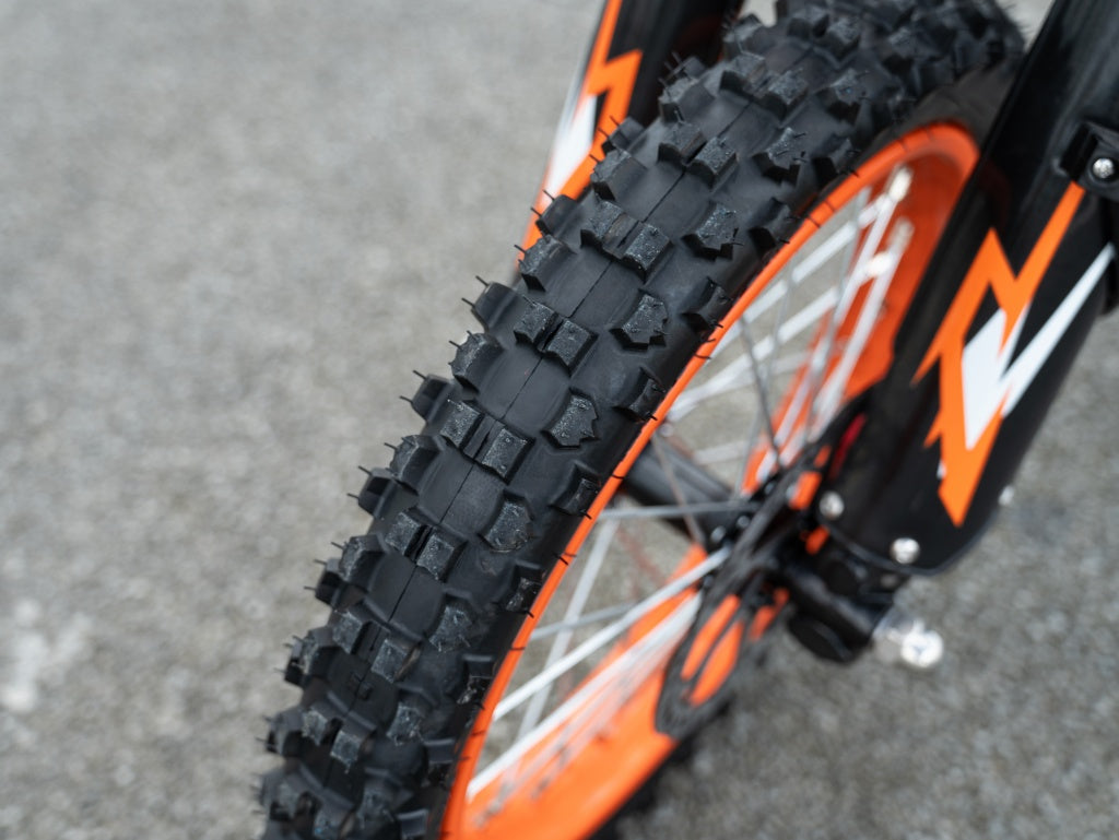 Close-up of GT54 electric mini motorbike knobby tire with orange rim and black spokes for off-road riding
