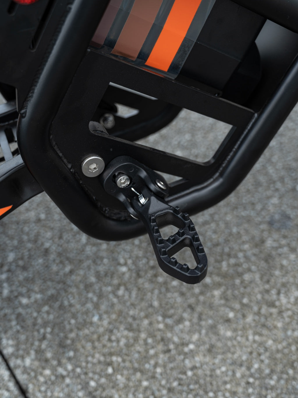 Close-up of GT54 electric mini motorbike footrest and frame detail on asphalt background